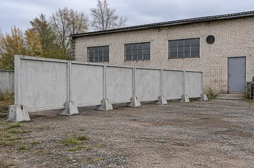 Панельный бетонный забор на опорах. Готовое ограждение. Панели на отдельных опорах у ремонтного склада. Визуализация.